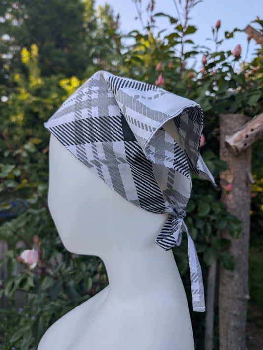 A mannequin head wearing a black and white checkered bandana-style headscarf.